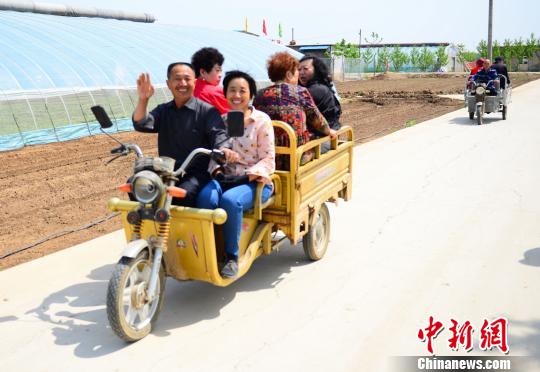 图为在东阿县草莓采摘基地里,村民们用三轮车拉着前来观光采摘的游客。 秋歌 摄 千年古县东阿发展“绿色经济” 激发美丽乡村多元活力