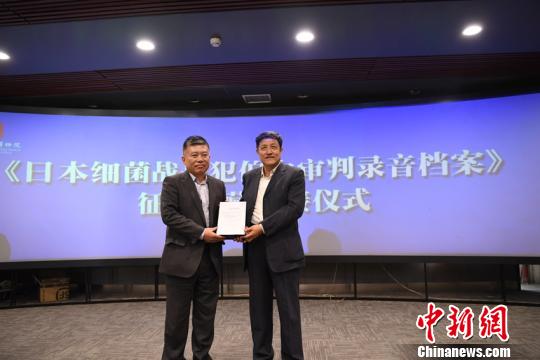 湖南红色记忆文化基金会理事长曹耘山(右)向伪满皇宫博物院院长王志强交接了“伯力审判录音档案”以及庭审照片等。 张瑶 摄 中国首次馆藏“伯力审判录音档案” 揭侵华日军细菌战罪行